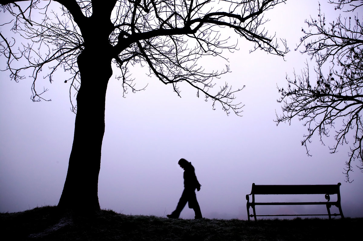 A person walking alone in thick fog.