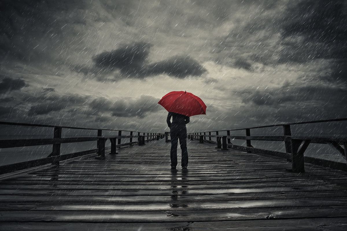 A woman holds a red umbrella on a fishing pier during a storm.